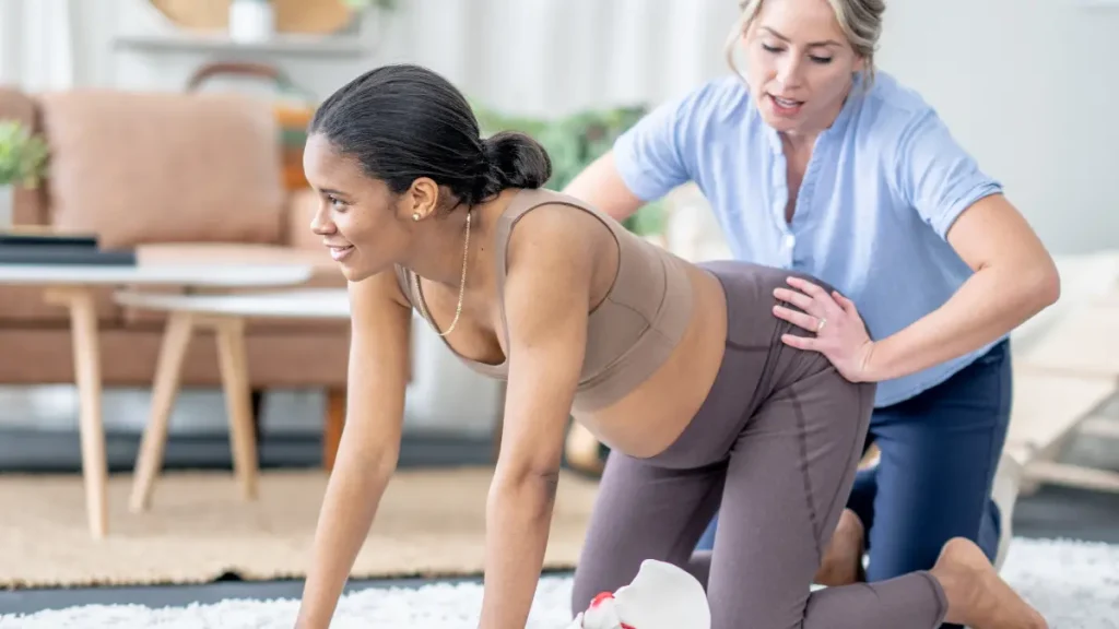 Grávida a realizar exercícios de fisioterapia com acompanhamento de uma fisioterapeuta durante a gravidez.
